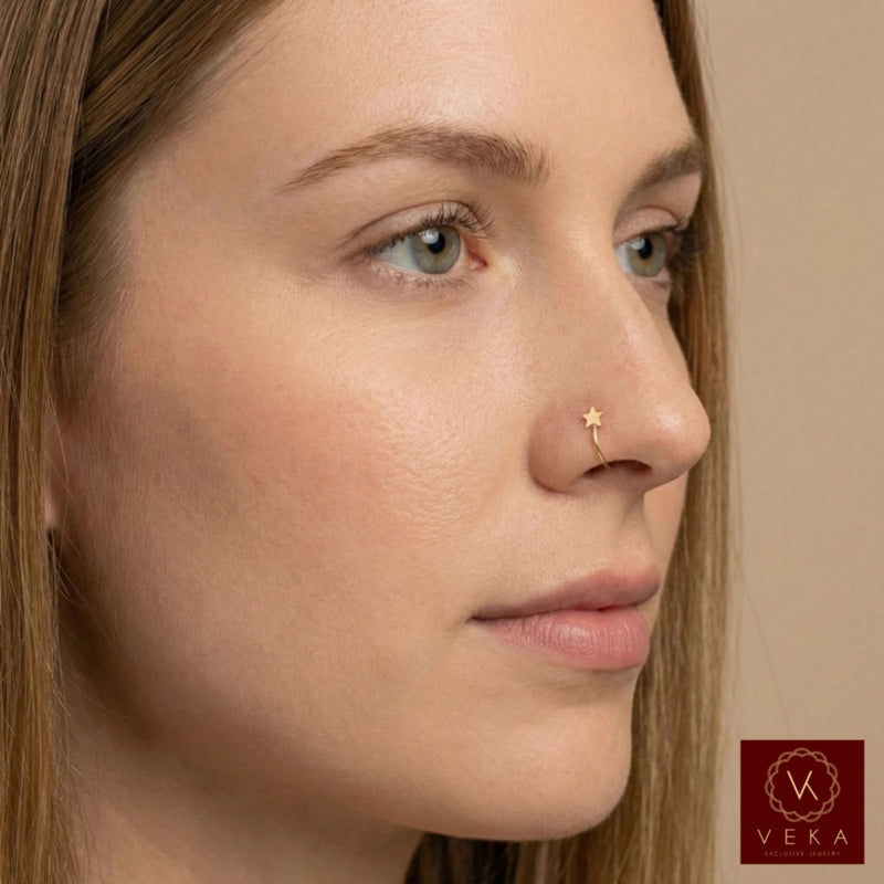 Close-up of a woman's face with a 14k yellow gold open nose hoop featuring a tiny star accent. Minimalist gold nose piercing jewelry by VEKA Jewelry
