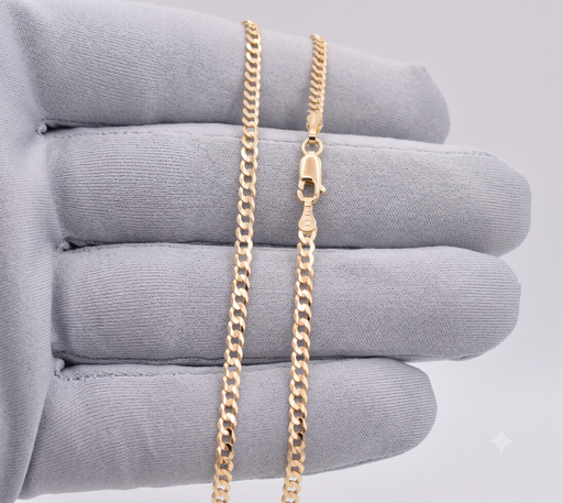 Close-up of 2.5mm solid 10k gold Italian curb link chain held in a gray gloved hand showing lobster claw lock and 10k stamp