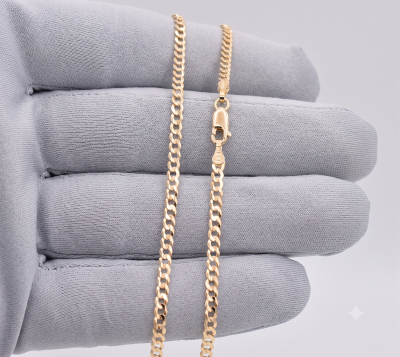 Close-up of 2.5mm solid 14k gold Italian curb link chain held in a gray gloved hand showing lobster claw lock and 10k stamp