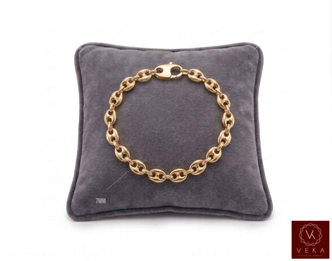 7mm puffed mariner link bracelet in 14K yellow gold displayed on a grey velvet pillow by Veka Jewelry