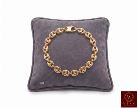 8mm puffed mariner link bracelet in 14K yellow gold displayed on a grey velvet pillow by Veka Jewelry