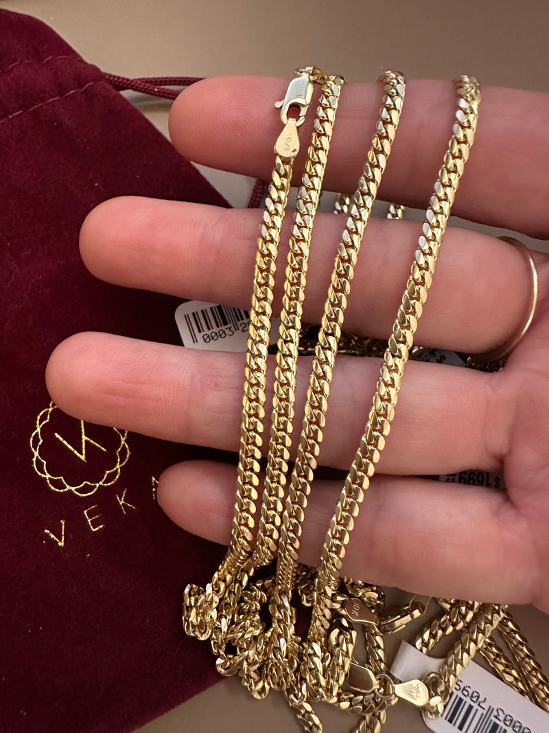 Gold chain held by a hand with a blurred background