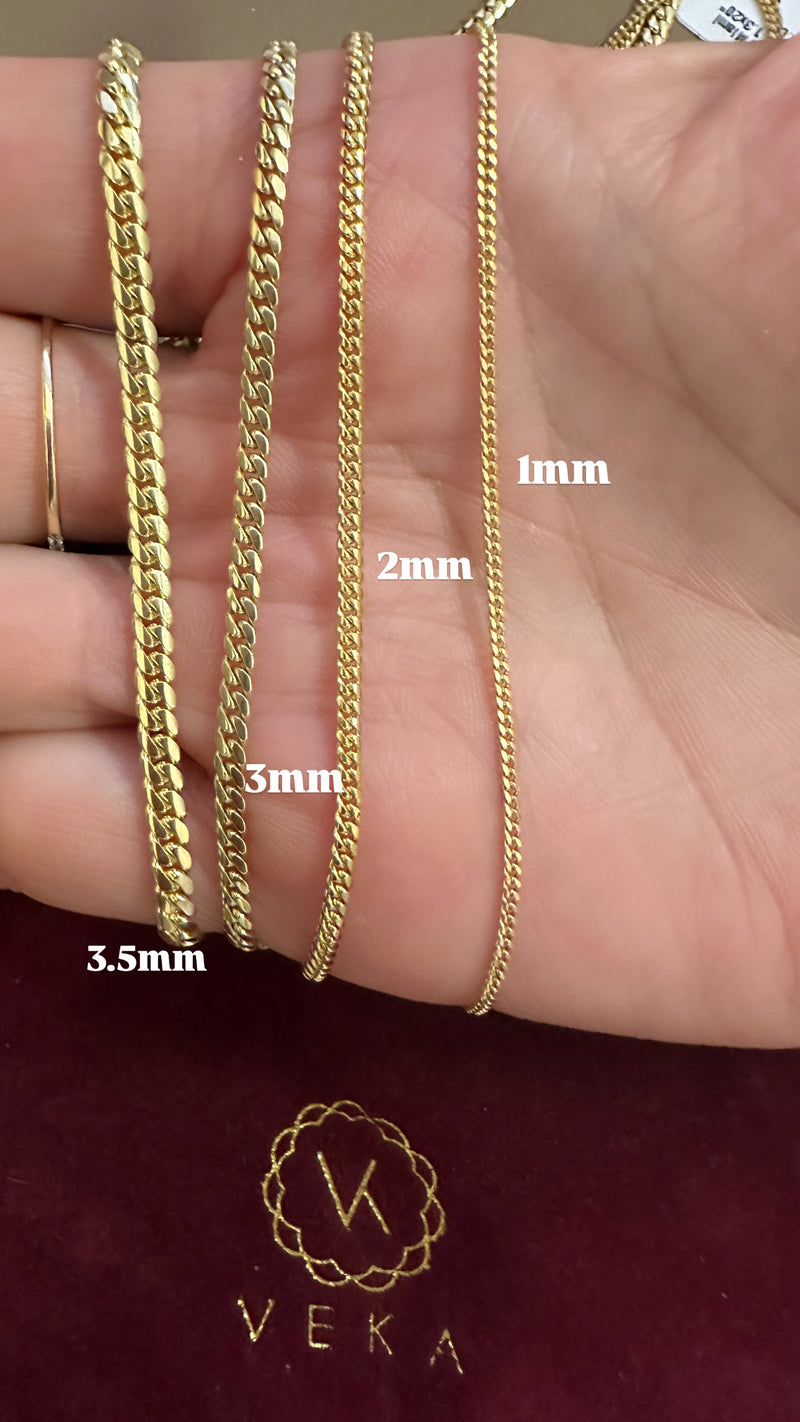 Gold chains of different widths displayed on a hand with Veka branding.