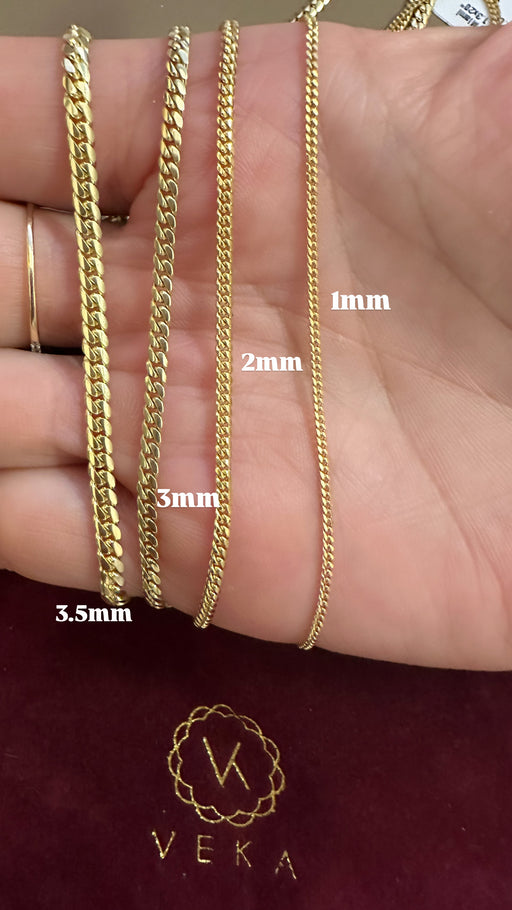 Gold chains of different widths displayed on a hand with Veka branding.