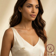 Beautiful Latina model wearing a delicate 14K gold open heart nipple piercing over a luxury silk cream dress - Veka Jewelry Lifestyle