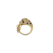 A 14 karat gold ring designed with a leopard motif, featuring small stones including green stones and a gold chain from face to tail on a white background