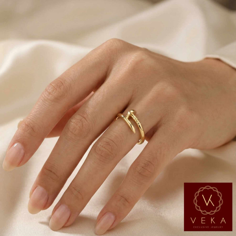 Hand wearing a women gold ring on a soft fabric background with Veka logo.