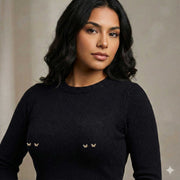 Woman wearing a black sweater with small decorative butterfly barbell piercings on a neutral background