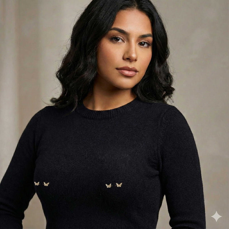 Woman wearing a black sweater with small decorative butterfly barbell piercings on a neutral background