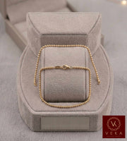 Professionally presented 14K solid yellow gold 2mm Moon Beaded polished bracelet on a plush grey suede jewelry stand with a matching VEKA box
