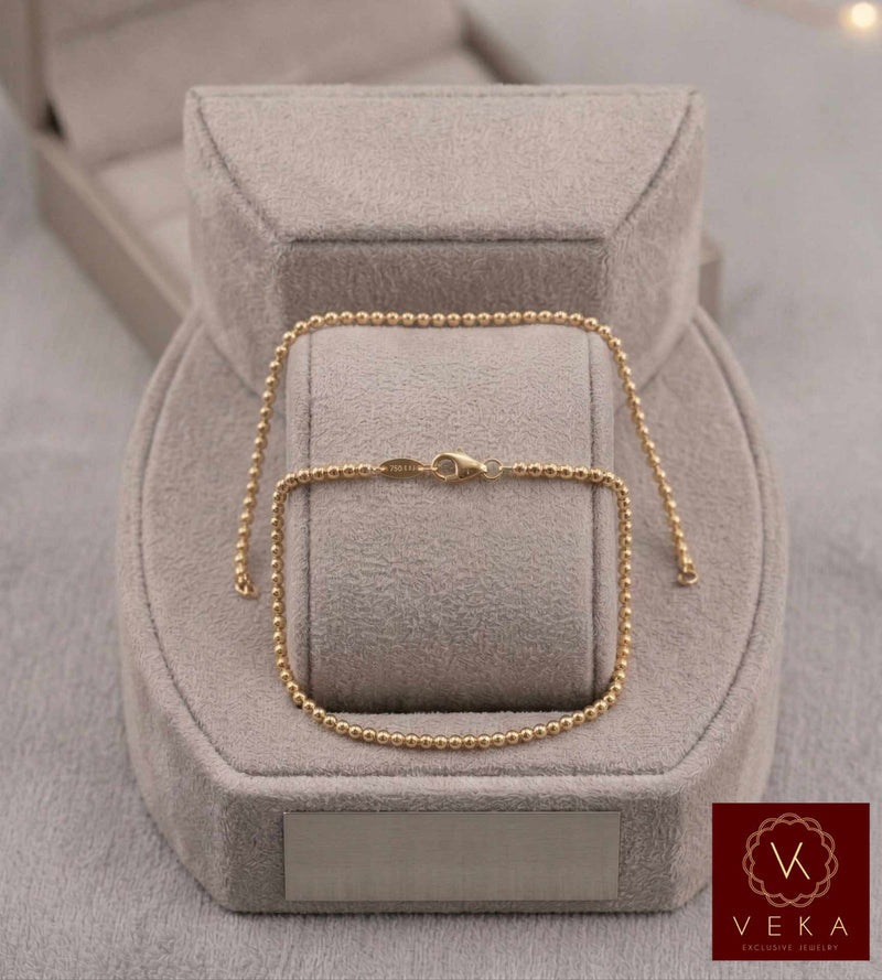 Professionally presented 14K solid yellow gold 2mm Moon Beaded polished bracelet on a plush grey suede jewelry stand with a matching VEKA box