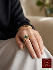 A woman's hand wearing the 14K gold cobra snake ring with emerald green stone, showing scale and fit