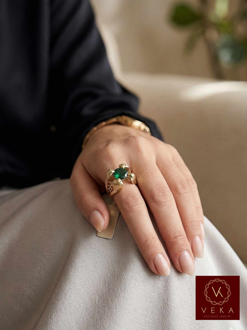 A woman's hand wearing the 14K gold cobra snake ring with emerald green stone, showing scale and fit