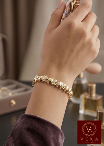 Close-up of a woman's wrist wearing an 8mm gold elephant link bracelet while holding a perfume bottle, showcasing the high-polish finish.