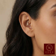 Close-up of an ear wearing a gold cartilage bezel piercing with Veka Jewelry logo in the corner.