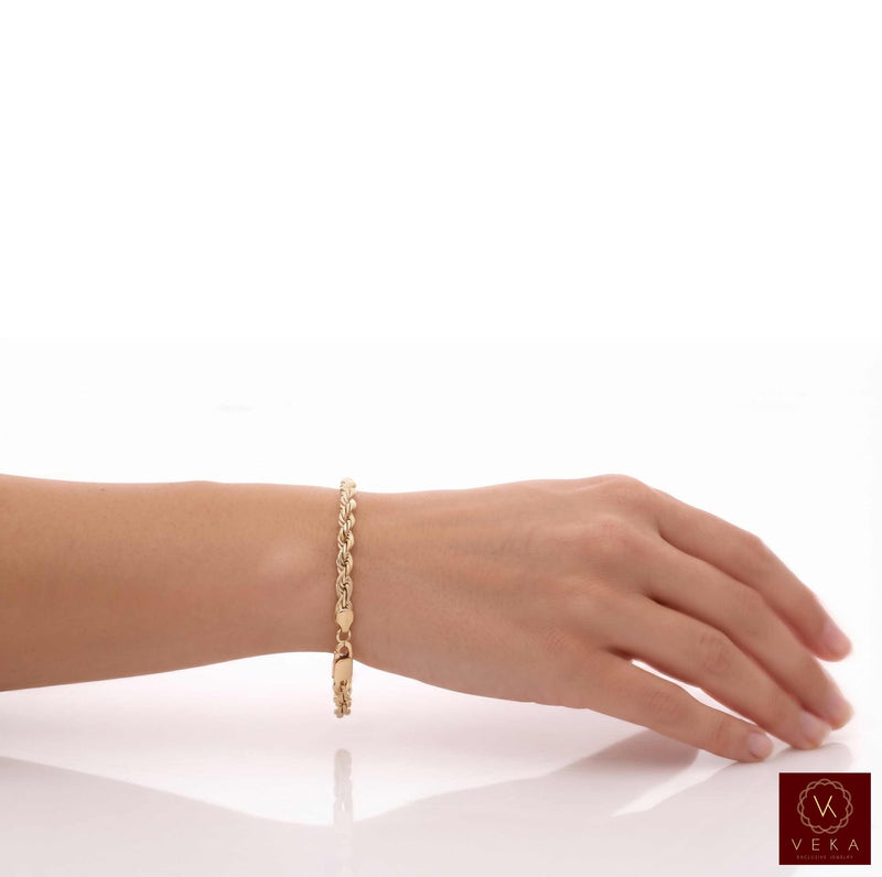 A real 14k gold chain solid rope bracelet with a lobster clasp worn on a person's wrist, shown against a clean white background with a reflection below at Veka Jewelry