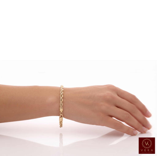 A real 14k gold chain solid rope bracelet with a lobster clasp worn on a person's wrist, shown against a clean white background with a reflection below at Veka Jewelry