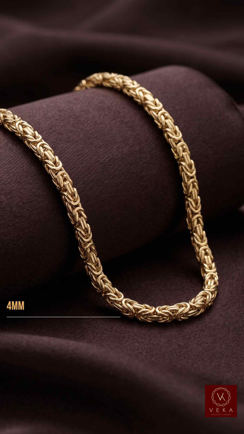 A polished 14k solid yellow gold Byzantine necklace draped elegantly on a dark, plush chocolate brown velvet surface, highlighting the metal's color and shine.