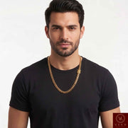 Man wearing a solid 10K yellow gold 7mm Miami Cuban link chain necklace over a black t-shirt, showcasing the fine jewelry fit and style.