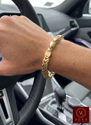 Close-up on-wrist shot of a man wearing a 10K yellow gold 6mm semi-solid Franco chain bracelet inside of a sport car with the console visible from Veka Jewelry