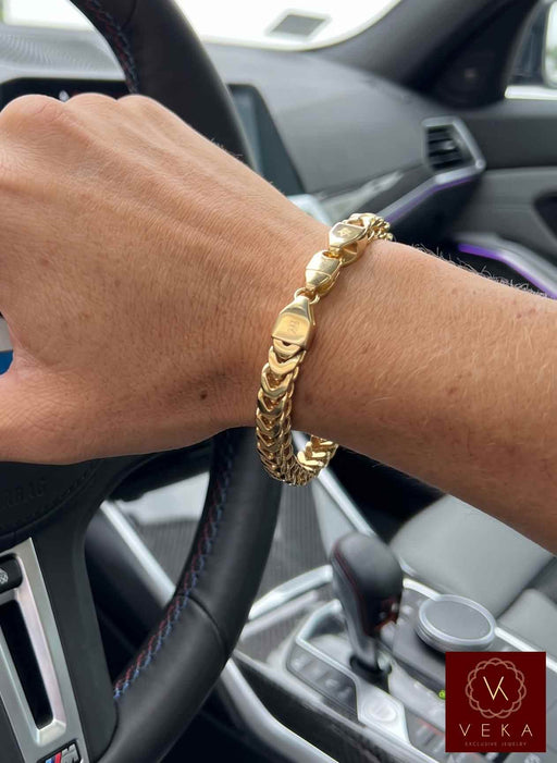 Close-up on-wrist shot of a man wearing a 10K yellow gold 6mm semi-solid Franco chain bracelet inside of a sport car with the console visible from Veka Jewelry