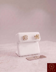 Pair of men's 10K yellow gold square moissanite stud earrings on a white display stand by Veka Jewelry.
