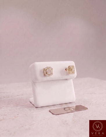 Pair of men's 10K yellow gold square moissanite stud earrings on a white display stand by Veka Jewelry.