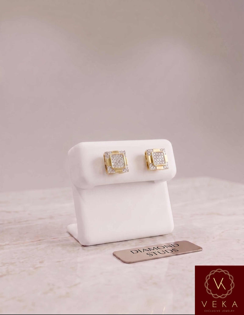 Men's 10K yellow gold 1/6 CTW round diamond stud earrings on a luxury white leather display stand with a VEKA JEWELRY logo