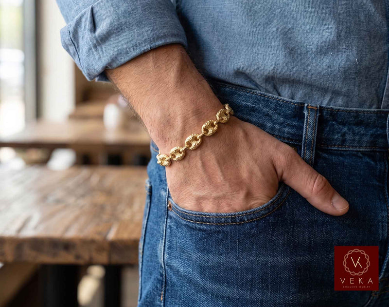 Lifestyle view of a man wearing the 10mm 10K yellow gold nugget textured puffed mariner link bracelet in casual jeans by Veka Jewelry