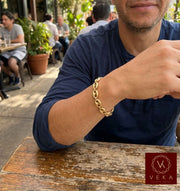 Lifestyle view of a man wearing the 12mm 14K yellow gold puff mariner link bracelet by Veka Jewelry