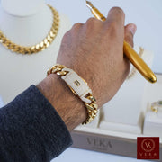 Close-up of a man wearing a hollow 14k gold 13mm Monaco link bracelet while holding a gold pen, Veka Jewelry
