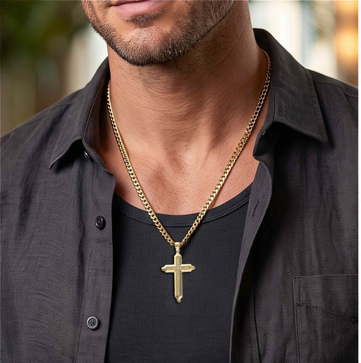 Male model wearing a 14K yellow gold beveled cross pendant paired with a classic gold Cuban link chain by Veka Jewelry.