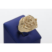 A heavy men's 14k yellow gold ring featuring an embossed Great Seal of the United States on a shield face and sculpted eagles on the sides, resting on a blue display stand.
