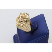 A Side view of A heavy men's 14k yellow gold ring featuring an embossed Great Seal of the United States on a shield face and sculpted eagles on the sides, resting on a blue display stand.