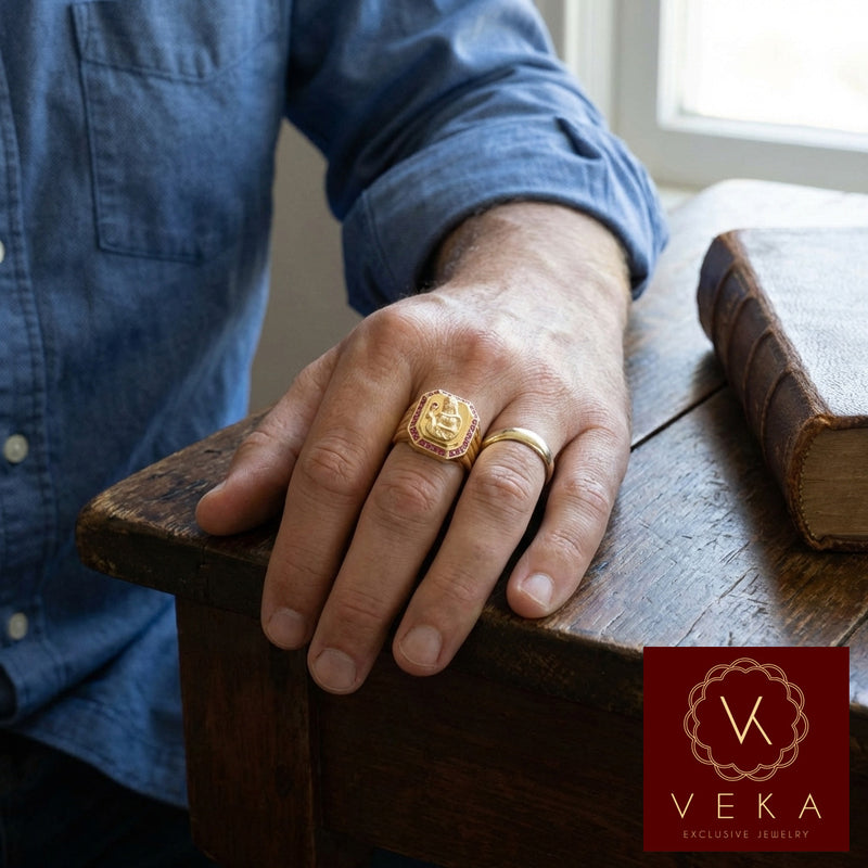 A stylish man wearing the Veka Jewelry 14K yellow gold Saint Barbara ring. The ring features a detailed gold relief of the Catholic Virgin surrounded by red synthetic rubies, showcased in a modern, professional setting.
