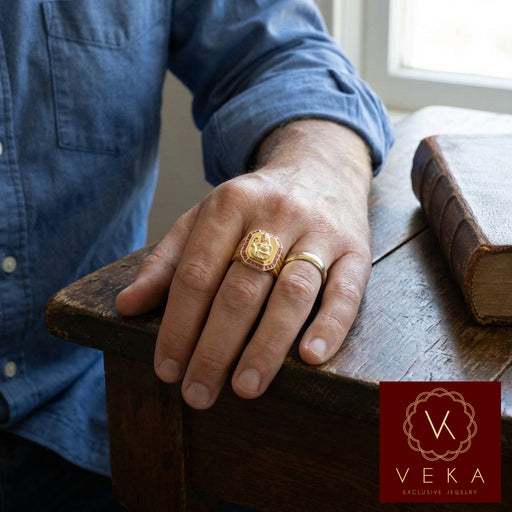 A stylish man wearing the Veka Jewelry 14K yellow gold Saint Barbara ring. The ring features a detailed gold relief of the Catholic Virgin surrounded by red synthetic rubies, showcased in a modern, professional setting.