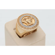An elevated three-quarter view of the Veka Jewelry 10k gold and 1/3 ctw natural diamond Medusa ring for men, showing the top face and a curve of the band. The detailed gold relief and sparkling pavé halo are displayed on a simple, cream-colored jewelry stand