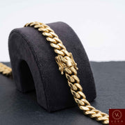 Close-up of a 7mm solid gold Miami Cuban link chain highlighting the premium secure box lock with safety clasps on a dark display stand