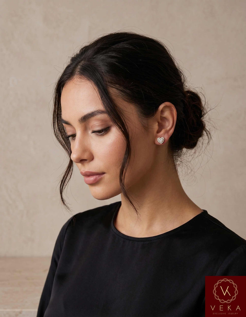 Elegant woman wearing 7mm 10K gold moissanite heart stud earrings with a neutral background.
