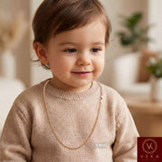 A smiling toddler wearing a solid 2mm Miami Cuban link 14k-gold chain in a small size, demonstrating its perfect fit, safety, and everyday style for babies and children by Veka Jewelry.