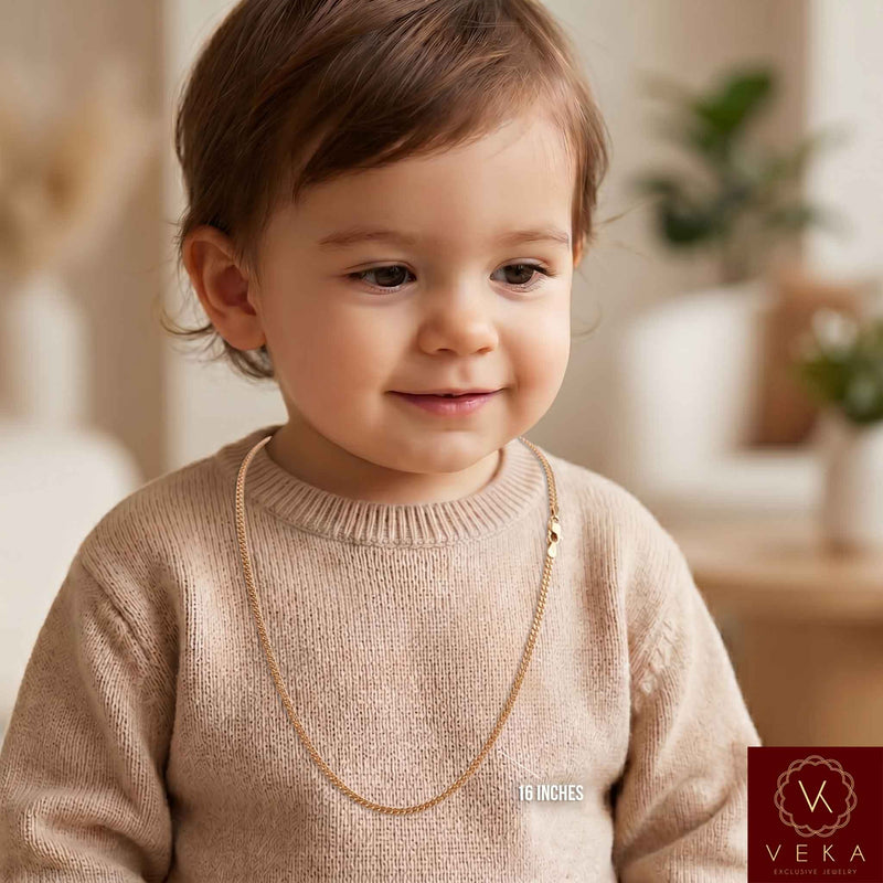 A smiling toddler wearing a solid 2mm Miami Cuban link 14k-gold chain in a small size, demonstrating its perfect fit, safety, and everyday style for babies and children by Veka Jewelry.