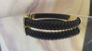 A video of a black leather bracelet with gold-colored accents and textured Cuban links, featuring a lobster lock clasp.