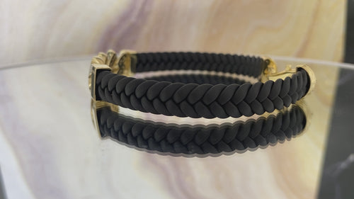 A video of a black leather bracelet with gold-colored accents and textured Cuban links, featuring a lobster lock clasp.
