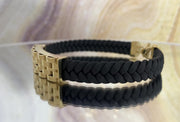 A video A 14 karat gold leather bracelet with a lobster lock clasp, crossed in a figure-eight style, displayed on a mirror 