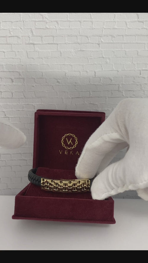 A video of A 14 karat gold leather bracelet with a lobster lock clasp, crossed in a figure-eight style, displayed on suede Veka Jewelry luxury burgundy box.