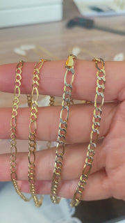 A video of 10k Gold Figaro anklets on a hand showing the sizes available.