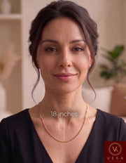 An elegant adult woman wearing a solid 2mm Miami Cuban link 14k solidgold chain. The image features a measurement guide highlighting the 18-inch length resting beautifully on the neckline, by Veka Jewelry
