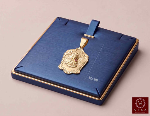 Solid 10K and 14K yellow gold Santa Barbara diamond cut medallion charm pendant resting on a blue leather jewelry display tray by Veka Jewelry