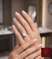 A hand model wearing the VEKA Exclusive Jewelry 14K yellow gold heart ring featuring a mother of pearl center surrounded by a diamond halo, styled with a classic French manicure in a luxury jewelry boutique setting