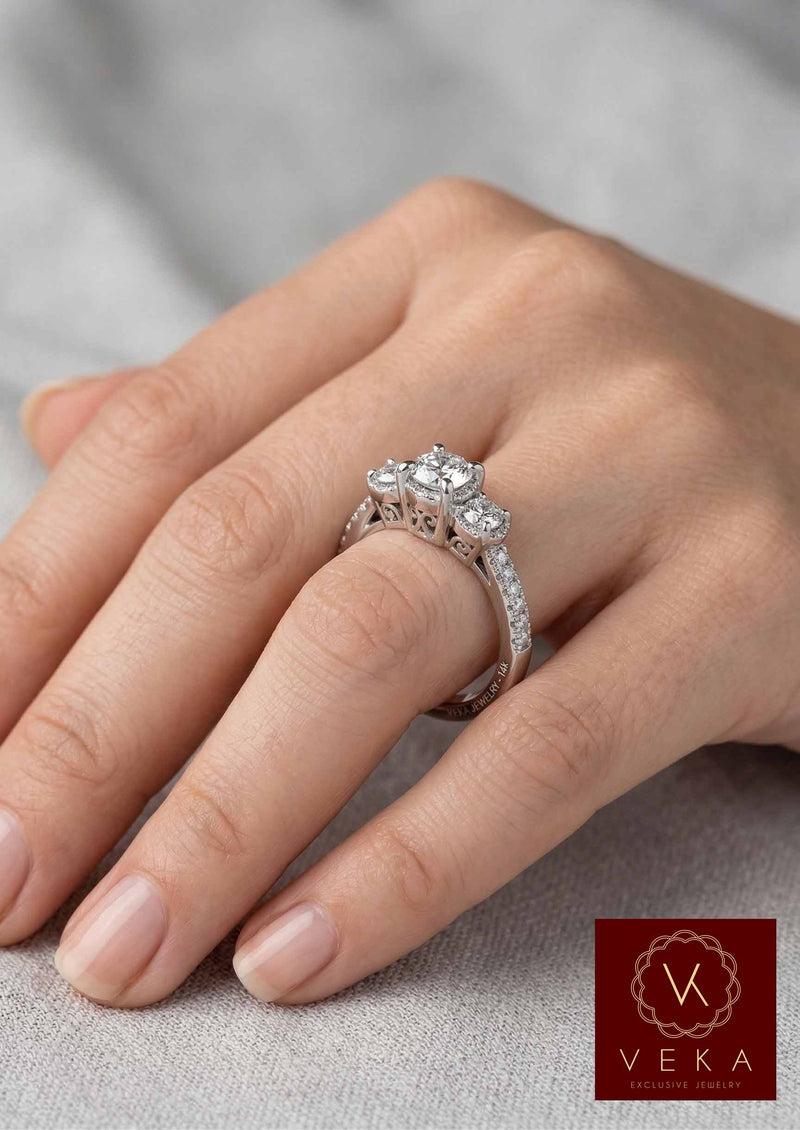Close-up of a woman wearing a round brilliant three-stone diamond ring with pavé band on her ring finger.